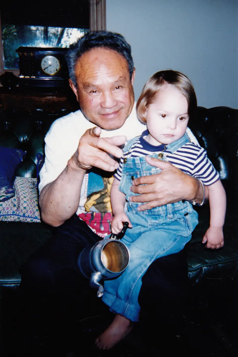 An old photo of a toddler sitting in the lap of her grandfather.