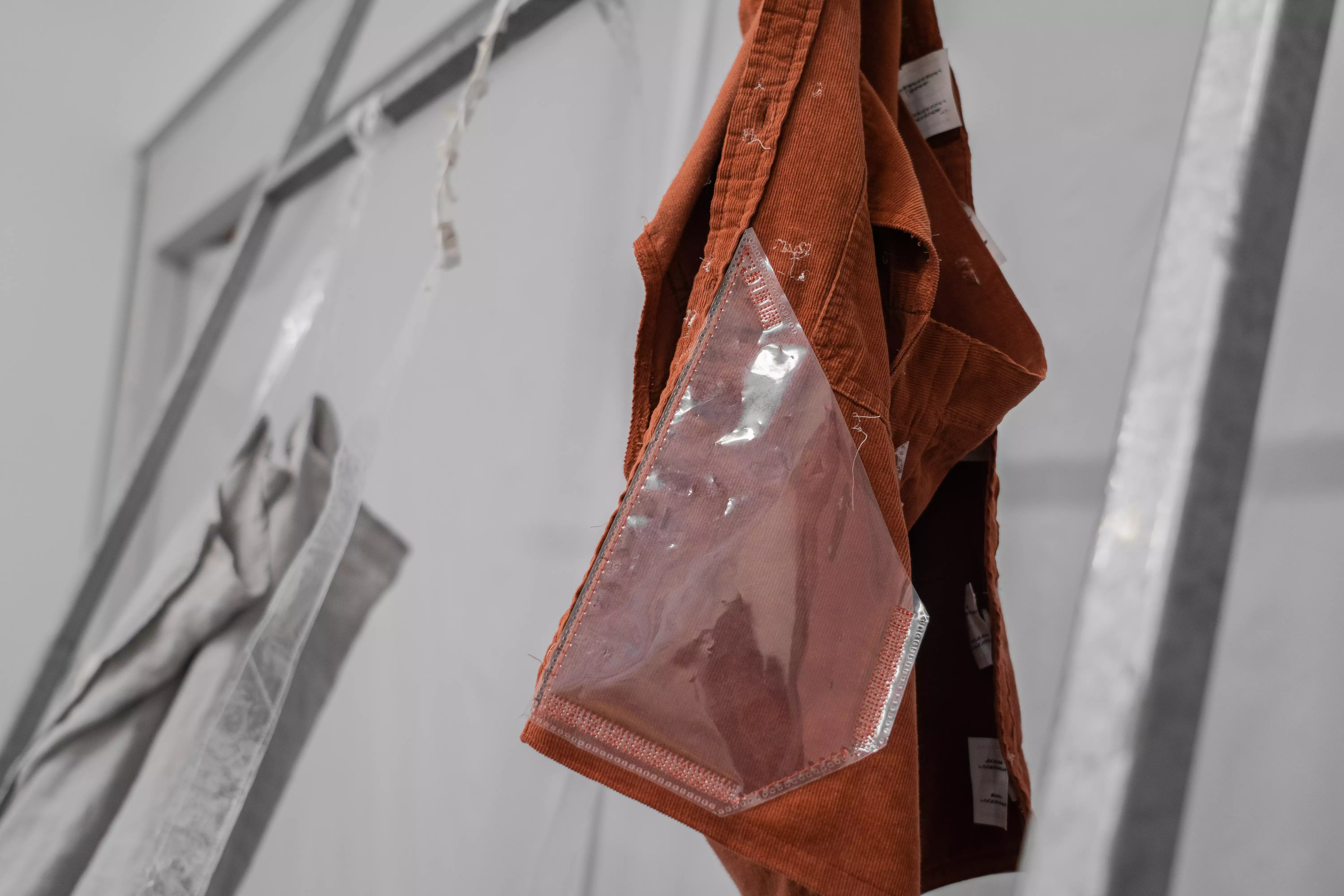 A detail shot of an experimental vest / bag hanging on display.