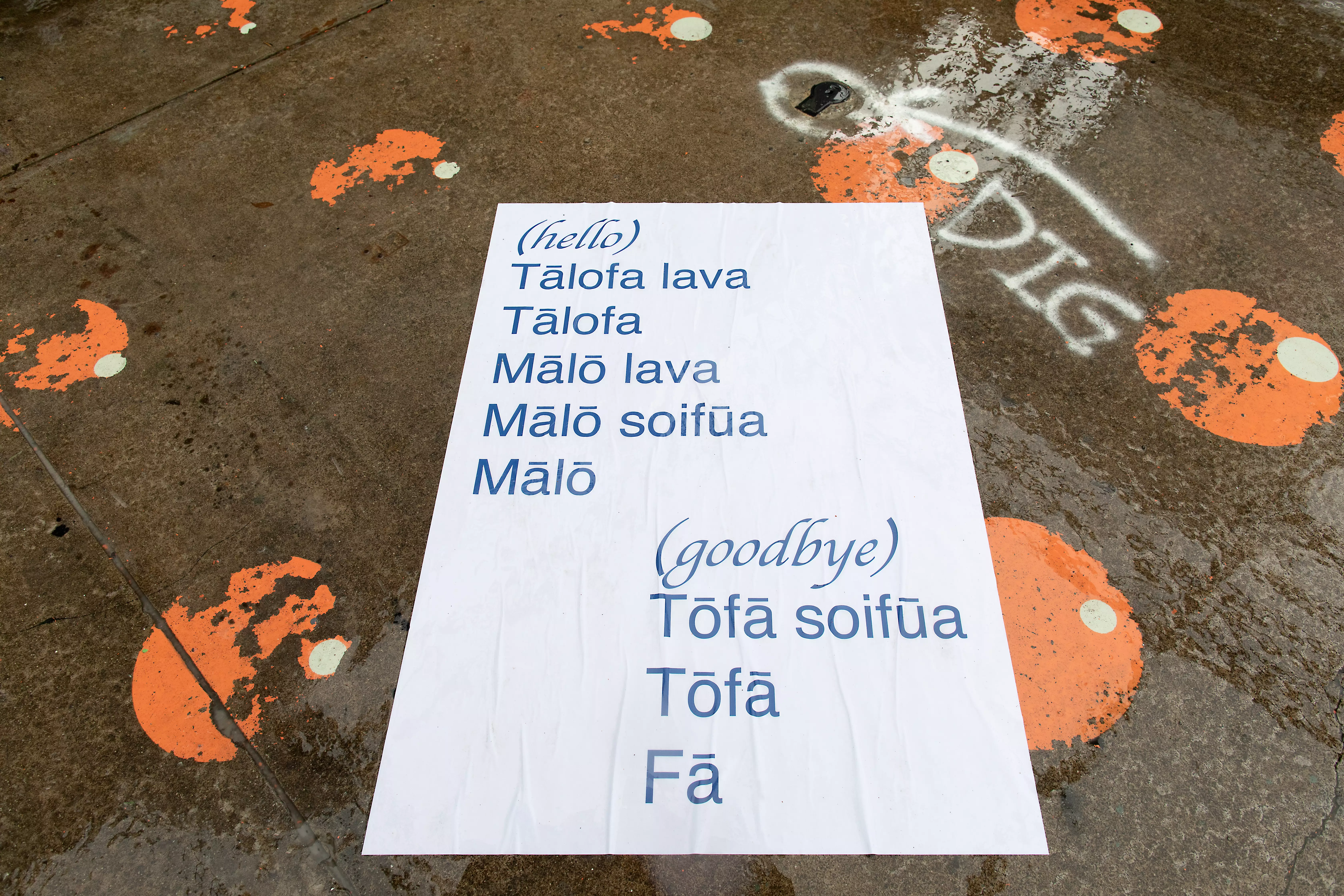 An installed poster depicting ways to say hello and goodbye in Samoan.