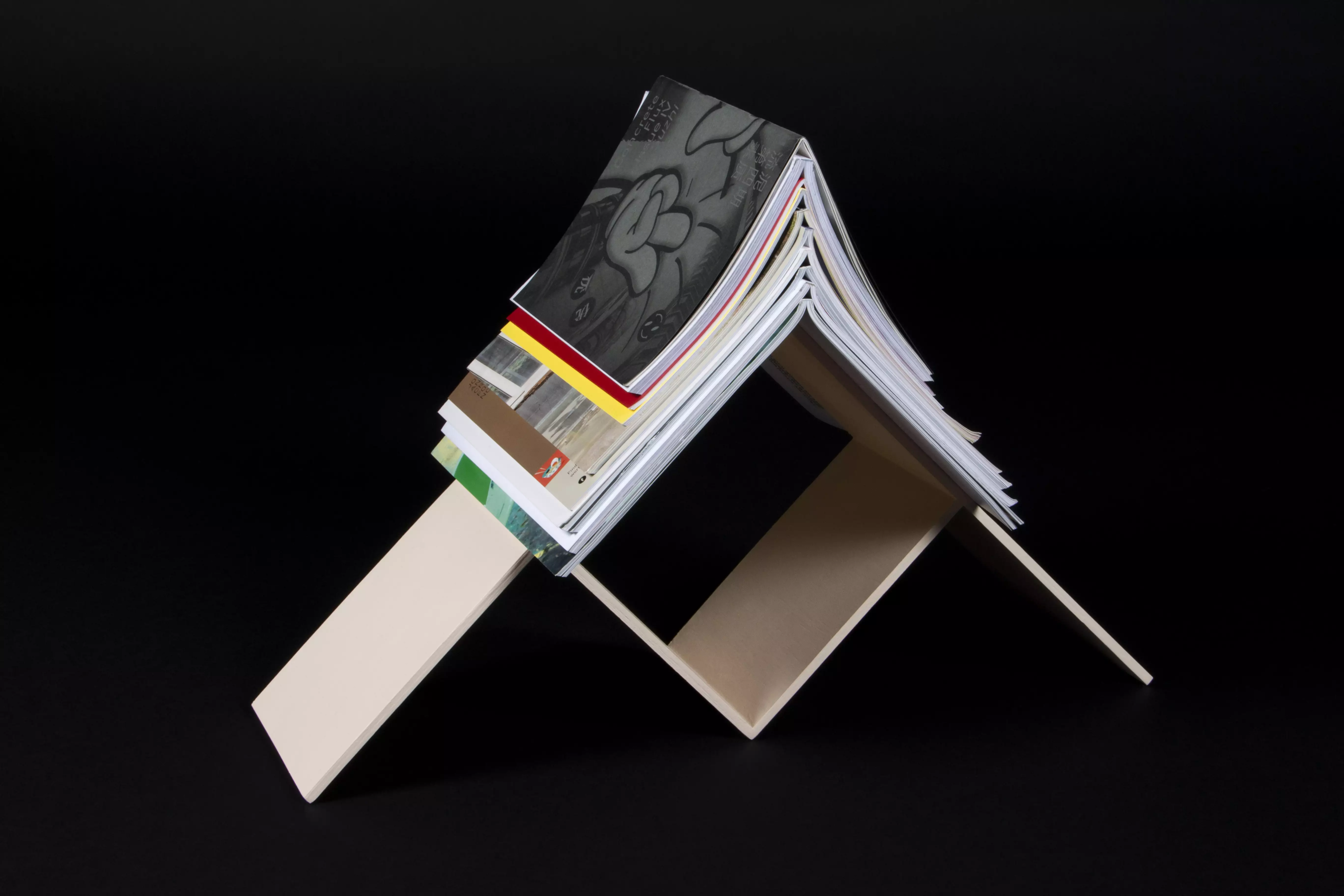 An experiemental bookshelf where the books are stacked on top of each other with their spines open.