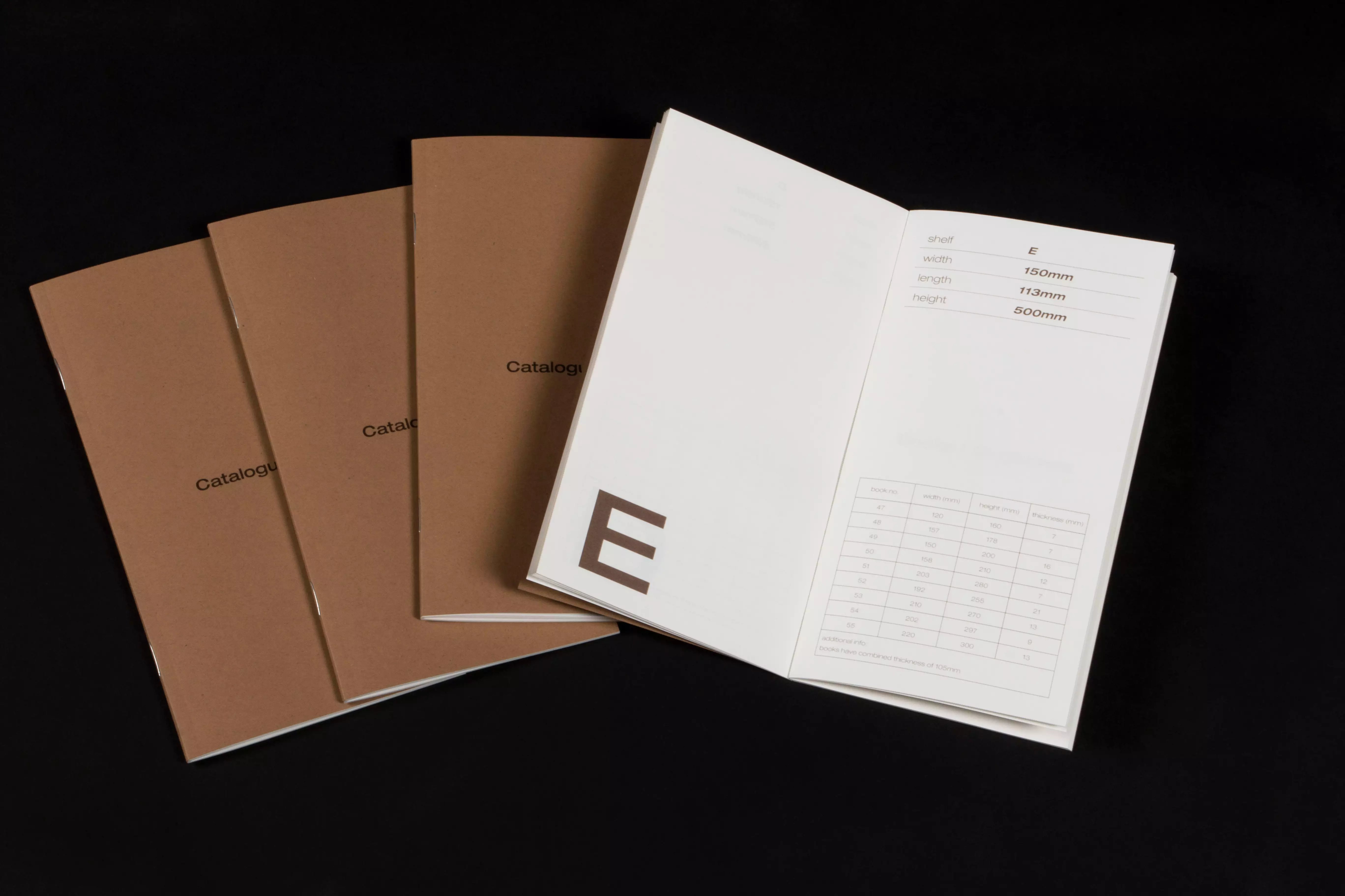 Four catalogues with brown covers that read 'catalogue' on the front. One of the catalogues lays open.